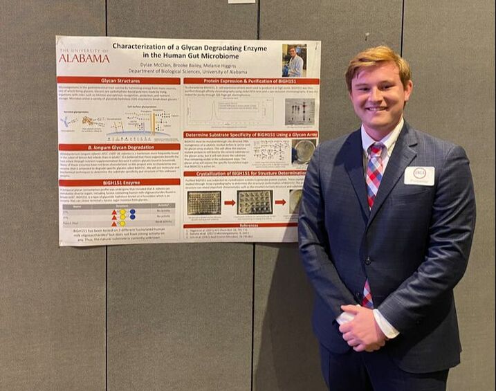 Dylan McClain standing by his research poster.