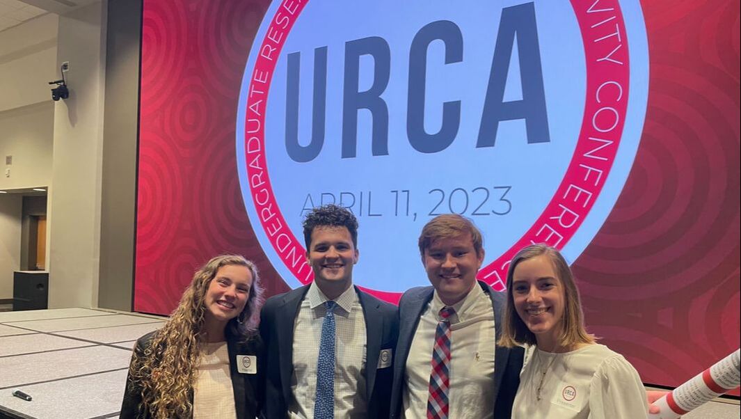 Malena, Jake, Dylan, and Brooke stading in front of the URCA sign.